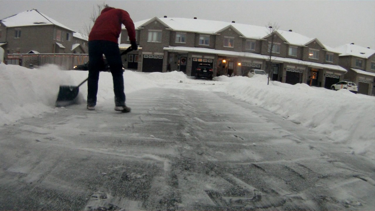 Professional movers clearing snow from a residential driveway